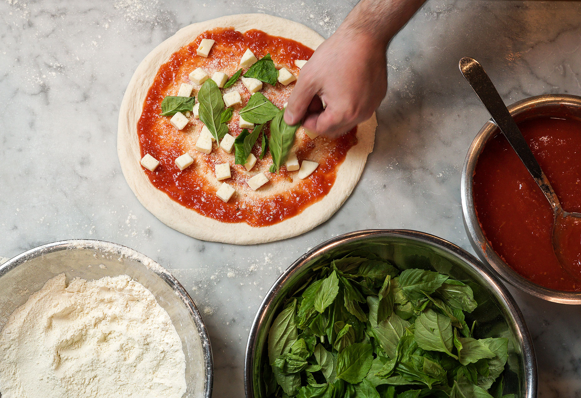 a chef sprinkling basil on a margherita pizza at da laposta