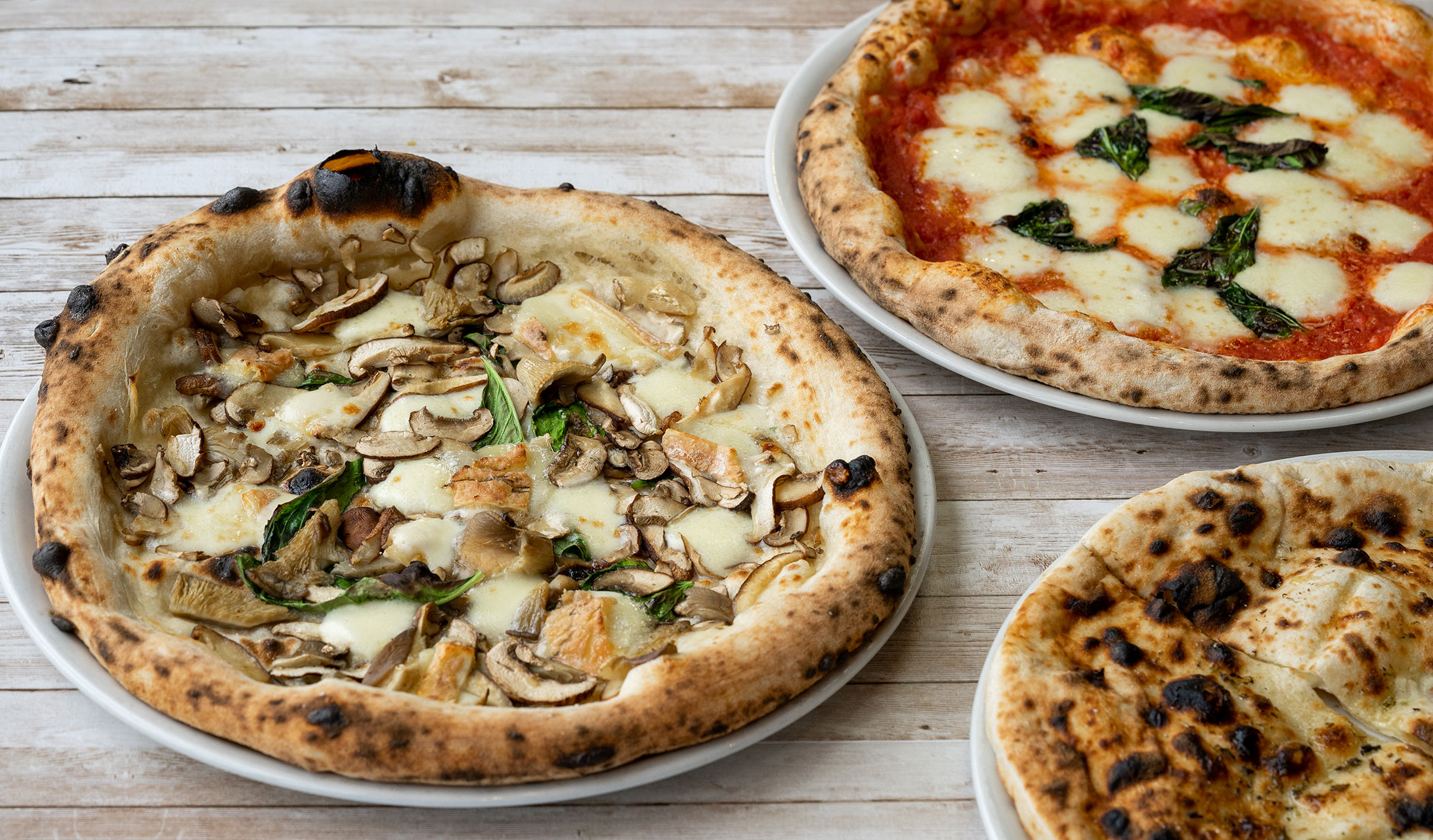a trio of pizzas on a table at da laposta