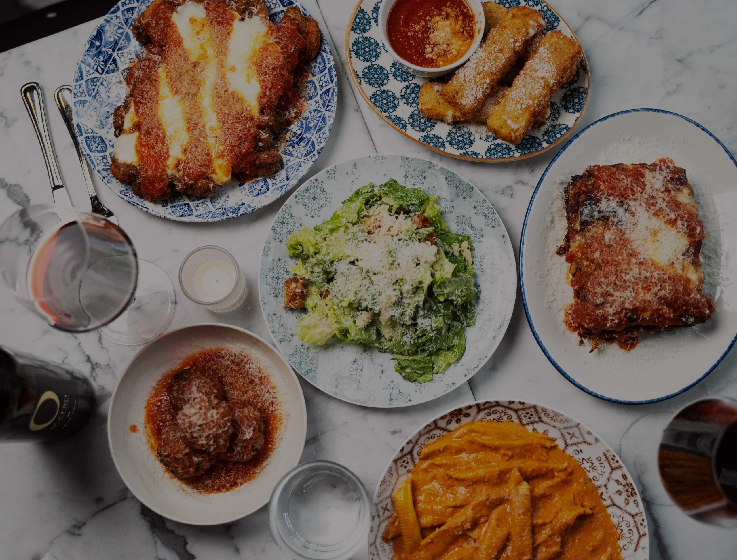 assortment of italian american dishes shot overhead on a marble table